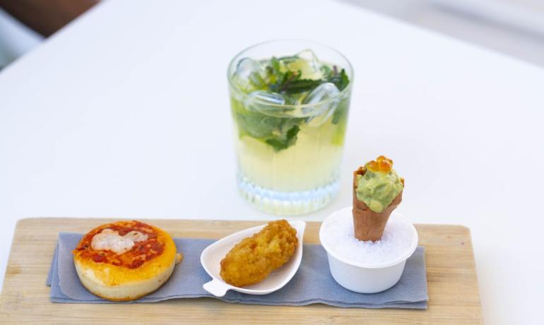 Elegante Vorspeisen auf Holztabletts, begleitet von einem erfrischenden Cocktail.
