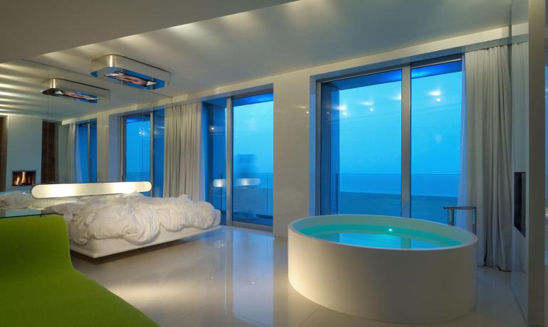Modernes Zimmer mit Wanne, Meerblick und sanfter Beleuchtung.
