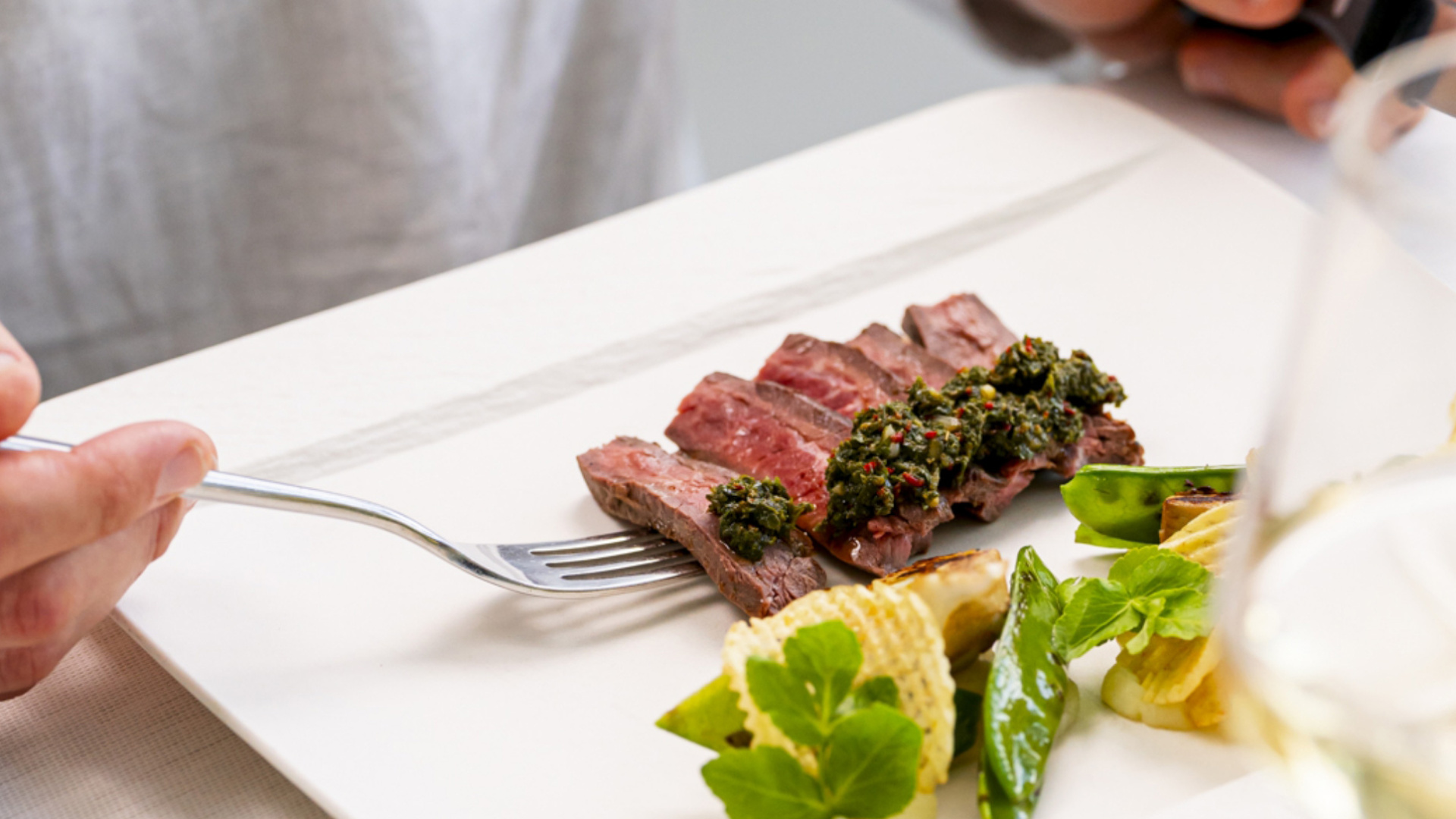 Fettine di carne con salsa verde e verdure su un piatto elegante.