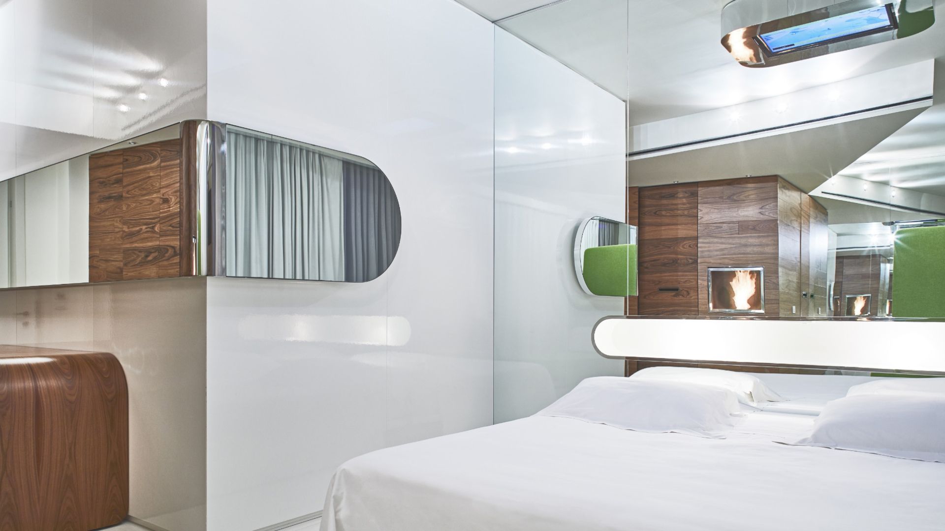 Camera moderna con letto bianco, pareti riflettenti e dettagli in legno e verde.