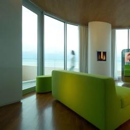 Modern living room with sea view, lit fireplace, and bright green sofa.