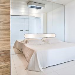 Minimalist, white, bright and modern room with mirrors and a cozy bed.