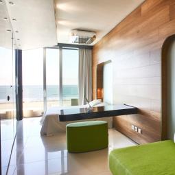 Chambre moderne avec vue sur la mer, bois chaleureux et mobilier vert.
