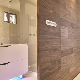 Bagno moderno con vasca, divisorio in legno e schermo integrato nella doccia.
