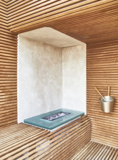 Sauna moderna con pareti in legno e secchio con mestolo.