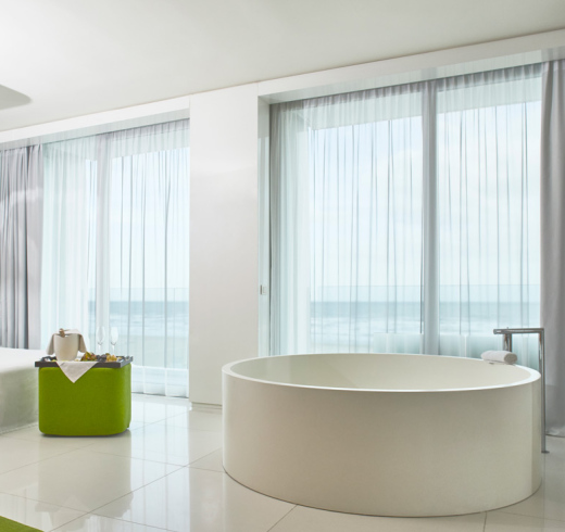 Camera moderna con vasca rotonda, vista mare e arredamento elegante.