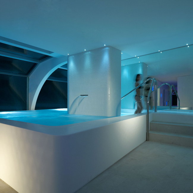 Piscina interna moderna con luci soffuse e design minimalista.