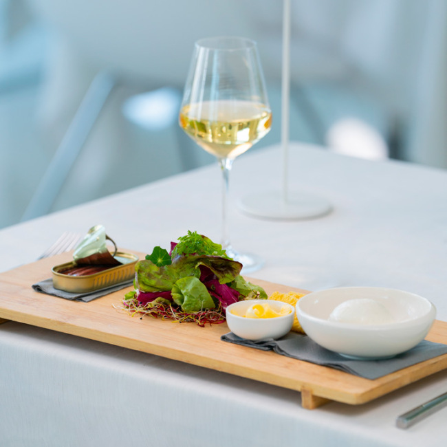 Elegantes Gericht mit Salat, Käse und Weißwein, edles Ambiente.