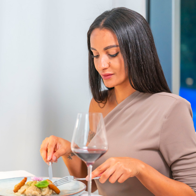 Elegante Frau speist mit Wein, intime und raffinierte Atmosphäre.