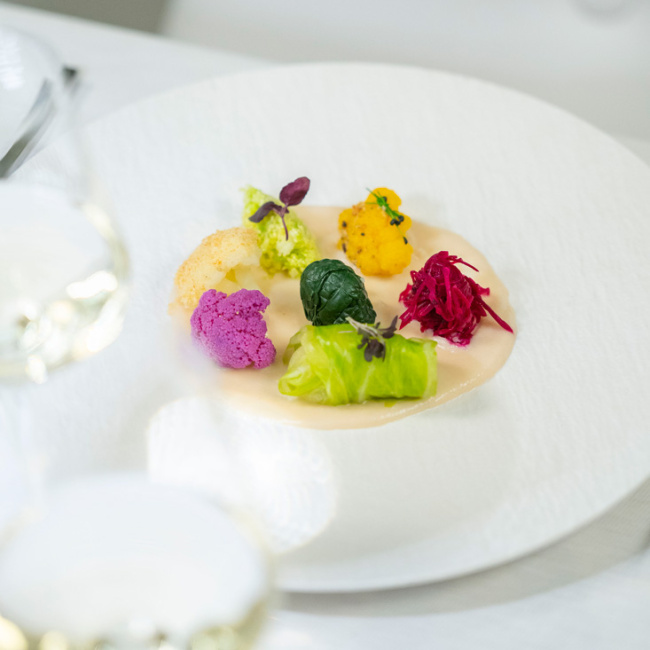 Piatto gourmet con verdure colorate su crema, servito elegantemente.