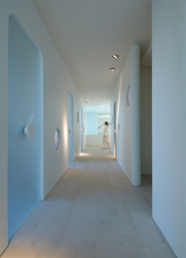 Corridoio moderno con porte blu e illuminazione soffusa, design minimalista e pulito.
