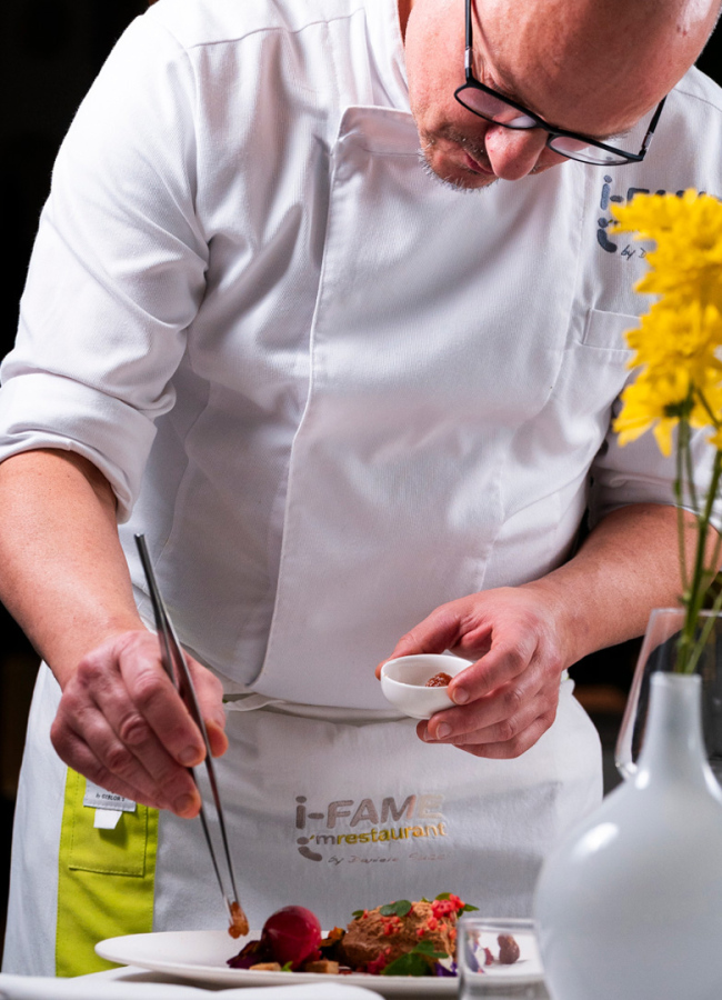 Chef prepara un piatto raffinato con attenzione ai dettagli, decorando con precisione.
