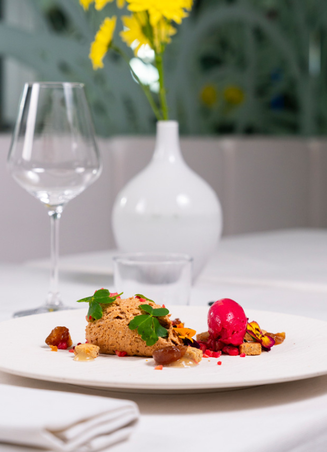 Elegantes Dessert auf edlem Tisch, lebendige gelbe Blumen, anspruchsvolle Atmosphäre.