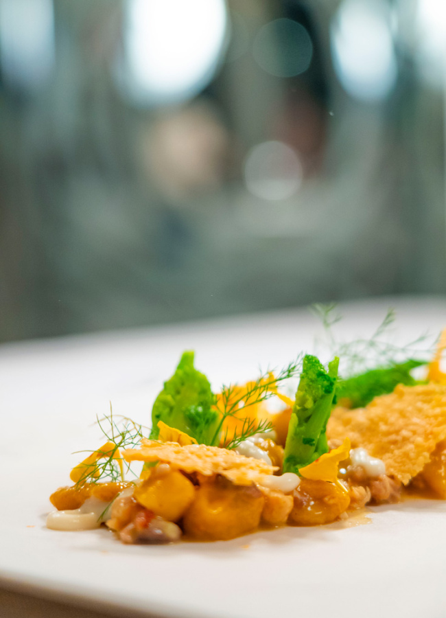 Piatto gourmet con ingredienti colorati e decorazioni eleganti su un piatto bianco.