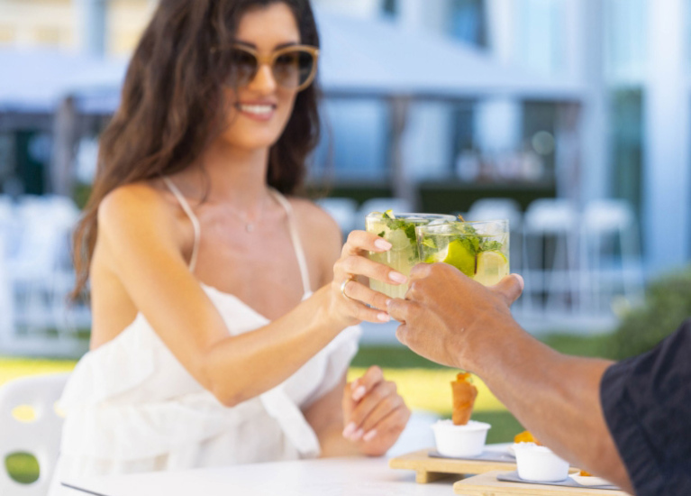 Due persone brindano con cocktail all'aperto in un ambiente rilassato.