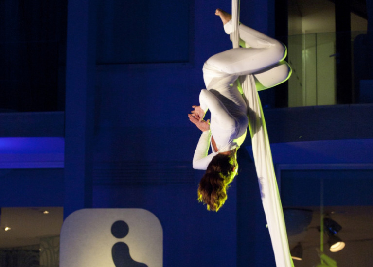 Artista di tessuti aerei esegue una performance acrobatica sospesa in un luogo urbano.