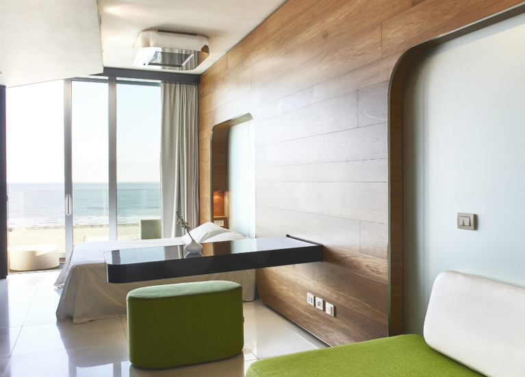 Camera moderna con vista mare, arredamento minimalista e dettagli in legno.