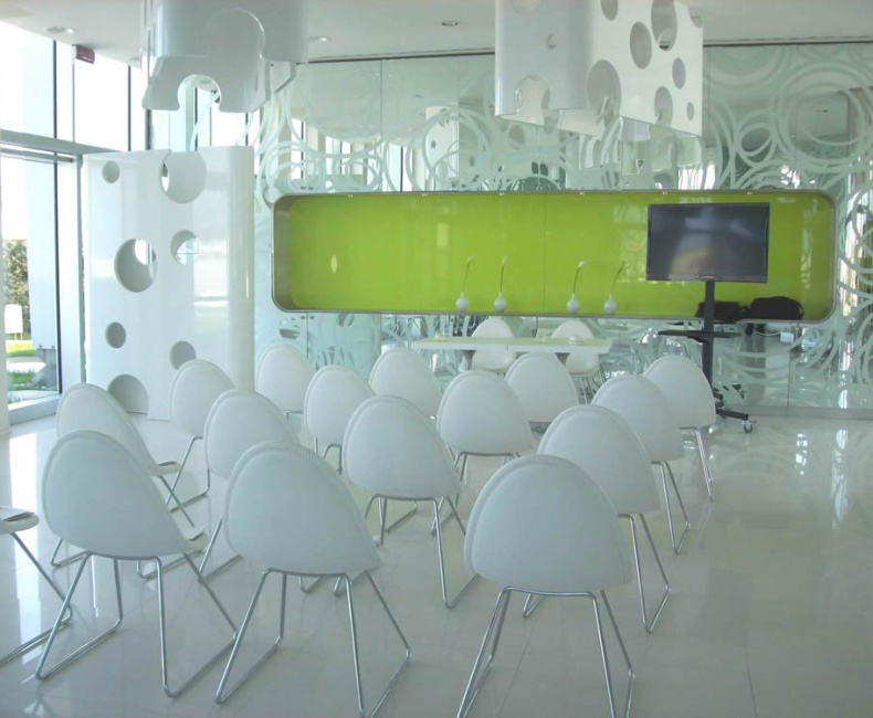Sala moderna con sedie bianche, pareti futuristiche e atmosfera luminosa e accogliente.